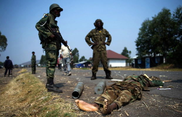 PHIL MOORE [AFP] - Soldats de l'armée congolaise se tiennent à côté d'un corps d'un prétendu M23 combattant dans Kanyarucinya, à environ 12 kms de Goma, dans l'est de la République démocratique du Congo le 16 Juillet 2013.